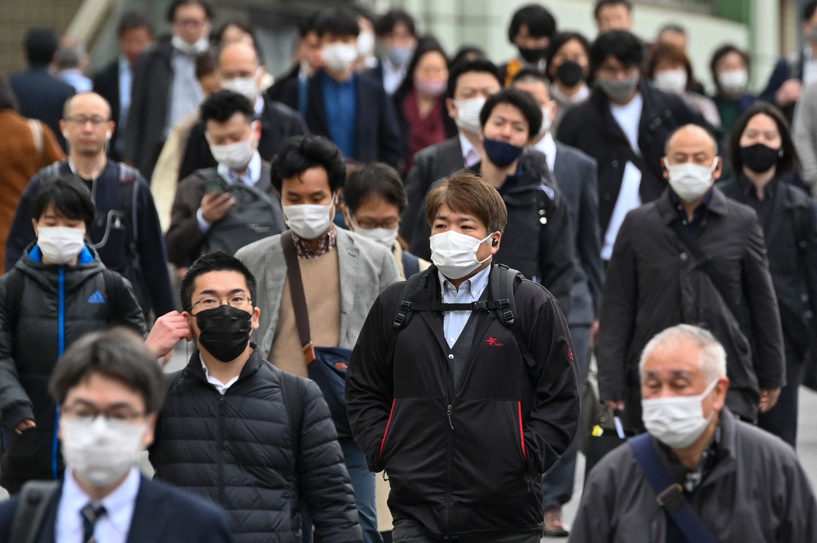 Passageiros caminham em uma rua no distrito de Shinjuku, em Tóquio, no primeiro dia de flexibilização do uso de máscaras, recomendando-as apenas em trens lotados e em hospitais ou casas de repouso — Foto: Kazuhiro NOGI / AFP