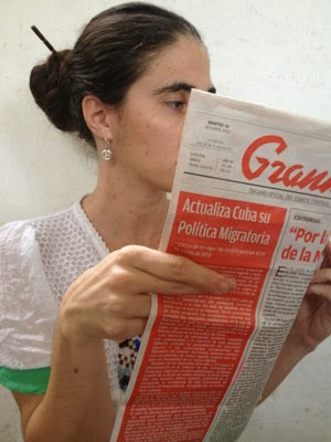 Foto posta por Yoaní Sanchéz no Twitter mostra a blogueira cruzando os dedos enquanto lê jornal oficial 'Granma' com a notícia sobre a nova lei migratória (Foto: Reprodução)