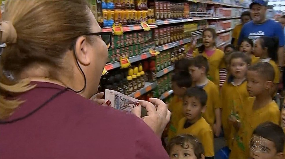Aparecida Bento de Paula, fundadora do projeto, mostra quanto cada criança tinha para gastar — Foto: TV TEM/Reprodução