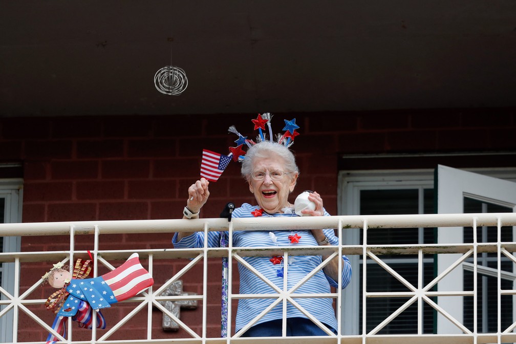 Lambeth House acena de sua varanda enquanto as cantoras de ópera Irini Hymel e Bryan Hymel cantam para os moradores em quarentena em Nova Orleans, nos EUA, em 20 de março — Foto: Gerald Herbert/AP