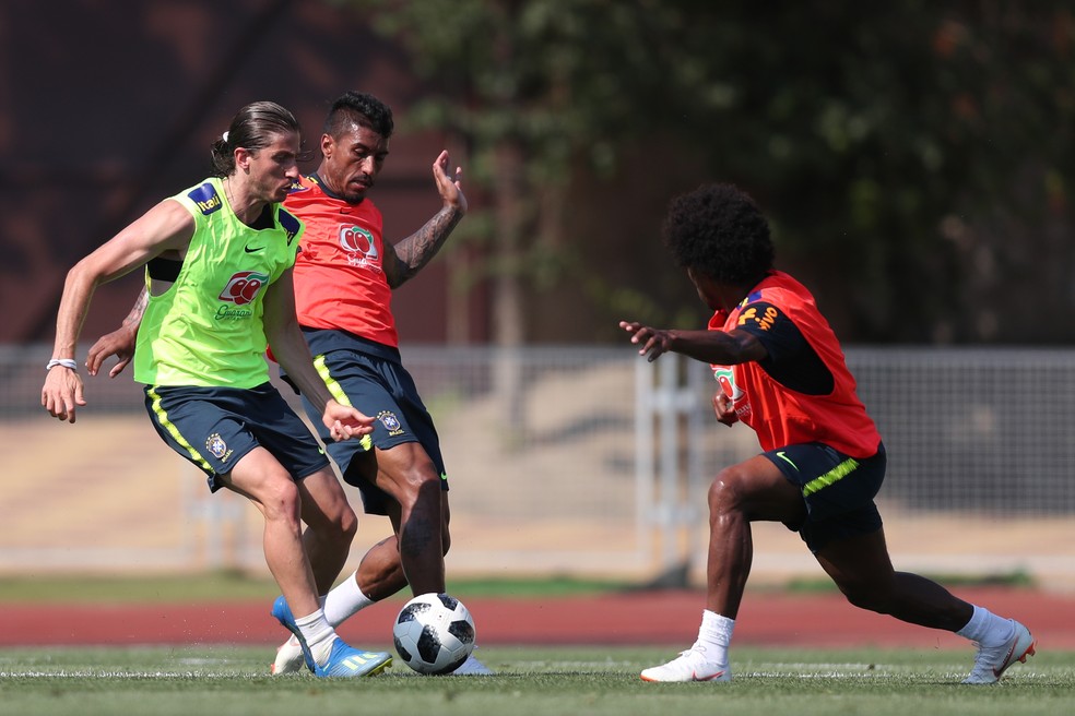 Willian e Paulinho, de colete vermelho, disputam a bola com Filipe Luís — Foto: Lucas Figueiredo/CBF