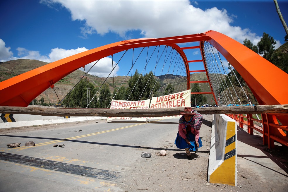 Mulher passa debaixo de tronco de árvore em ponte interditada em Cusco pelos protestos que pedem renúncia da presidente do Peru, Dina Bolutarte, em 07 de janeiro de 2023.   — Foto: Hugo Courotto/ Reuters