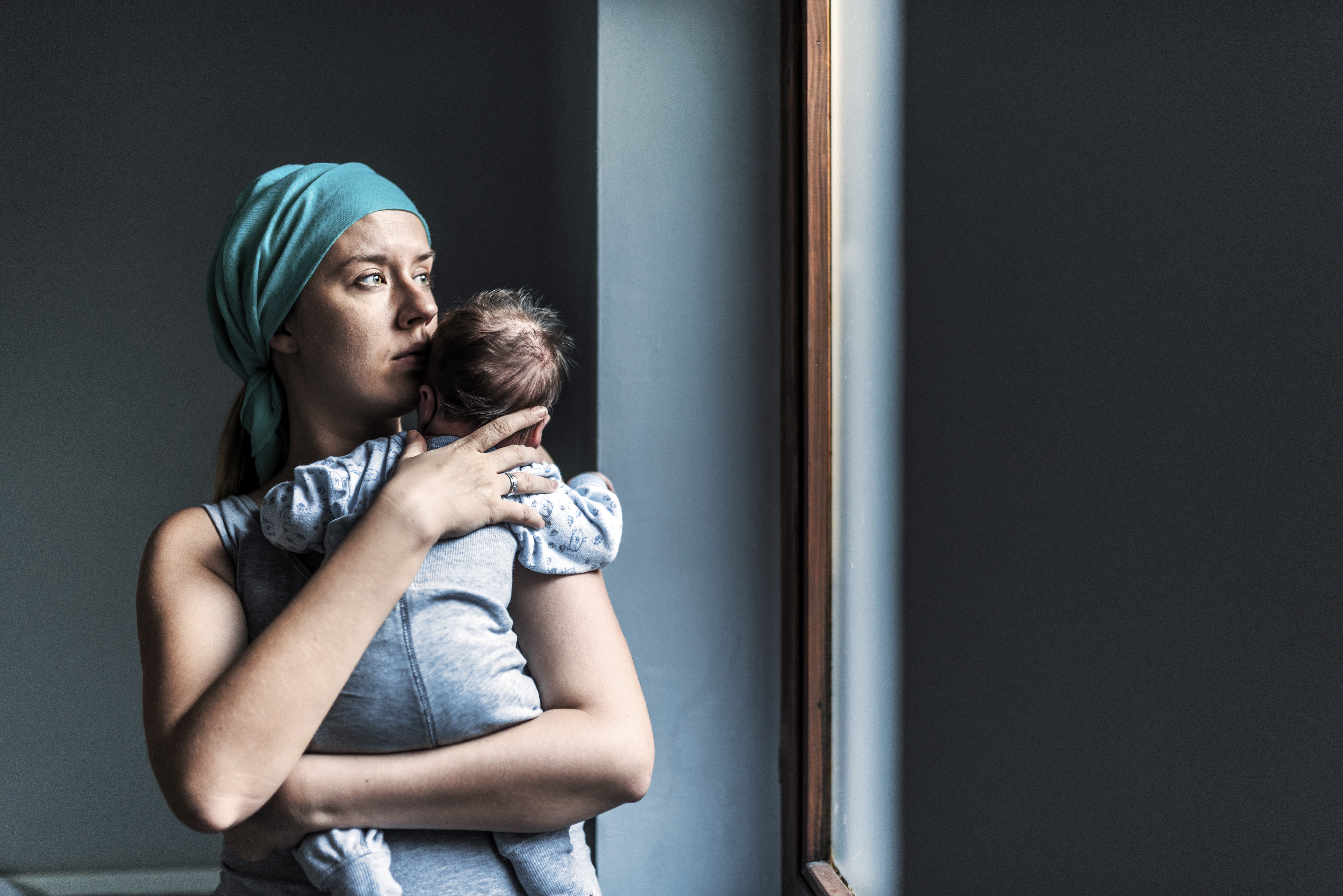 Mãe segurando bebê e olhando pra janela (Foto: Getty Images)
