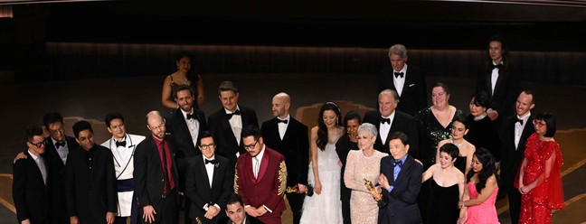O produtor Jonathan Wang discursa ao receber o Oscar de Melhor Filme por 'Tudo em todo o lugar ao mesmo tempo', acompanhado no palco pelos diretores e artistas — Foto: Patrick T. Fallon / AFP