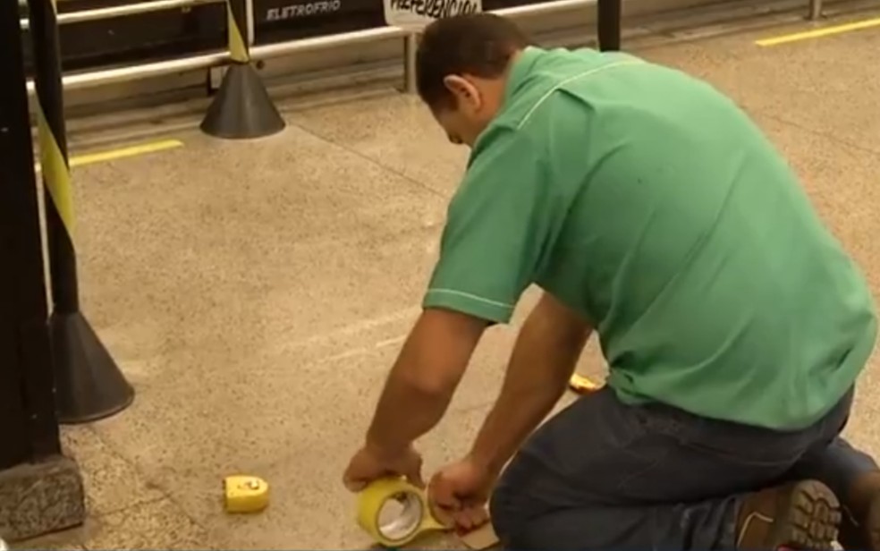 Funcionário demarca distância no chão entre os clientes, em Anápolis, Goiás — Foto: Reprodução/TV Anhanguera