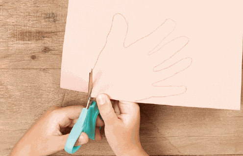 Peça para seu filho dobrar o papel e desenhar a palma da mão sobre o papel, rente à dobra.