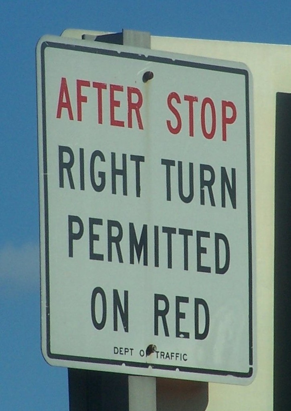 Placa que permite a conversão livre à direita em Nova York. Tradução: após parar, conversão livre à direita no farol vermelho.  — Foto: Wikimedia Commons