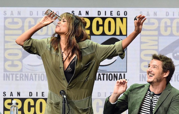 A atriz Halle Berry virando o copo de whisky enquanto é observada pelo ator Pedro Pascal (Foto: Getty Images)