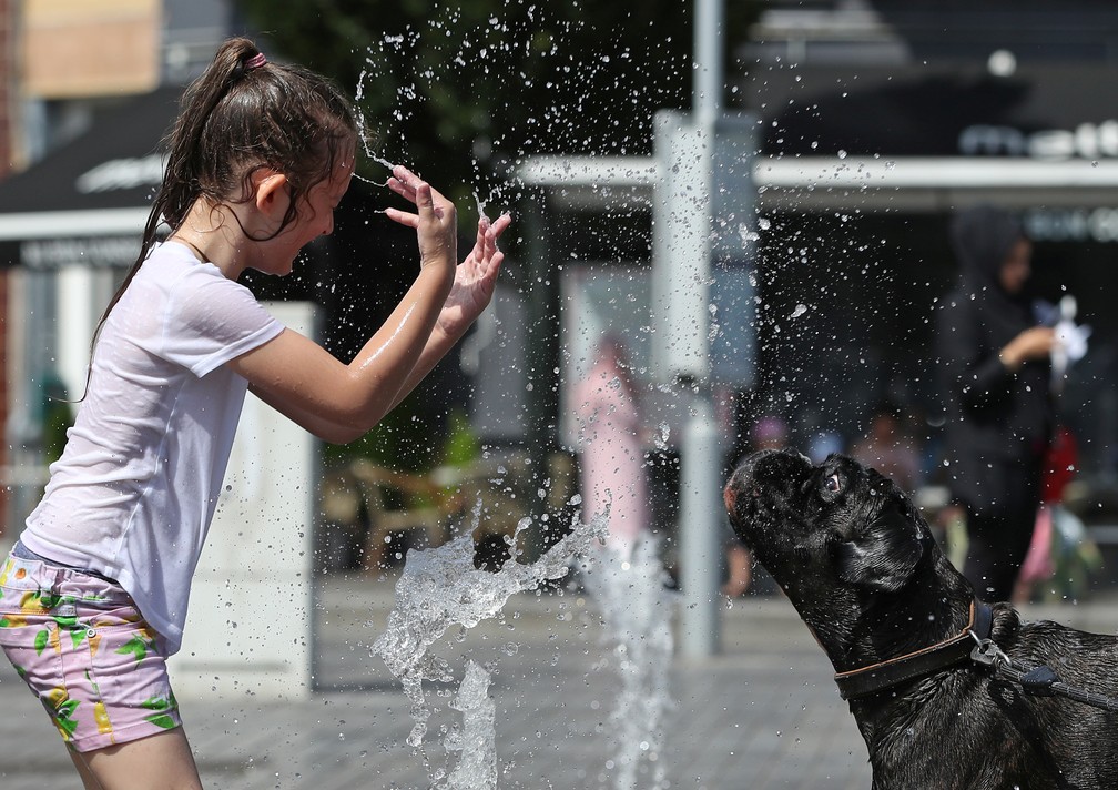 Menina brinca com cachorro em dia quente em Bruxelas, na BÃ©lgica â Foto: Yves Herman/Reuters