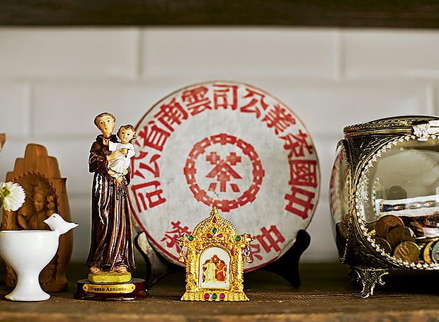 Na estante da sala, a imagem de Santo Antônio divide espaço com prato decorativo chinês e miniatura de templo budista comprado na Índia (Foto: Victor Affaro/Editora Globo)