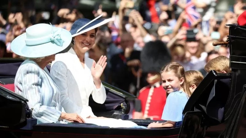 Os primeiros a aparecer foram Catherine (Kate), Duquesa de Cambridge, e Camilla, Duquesa da Cornualha, em uma carruagem puxada por cavalos — acompanhadas pela princesa Charlotte, pelo príncipe George e pelo príncipe Louis. (Foto: Reuters via BBC News)