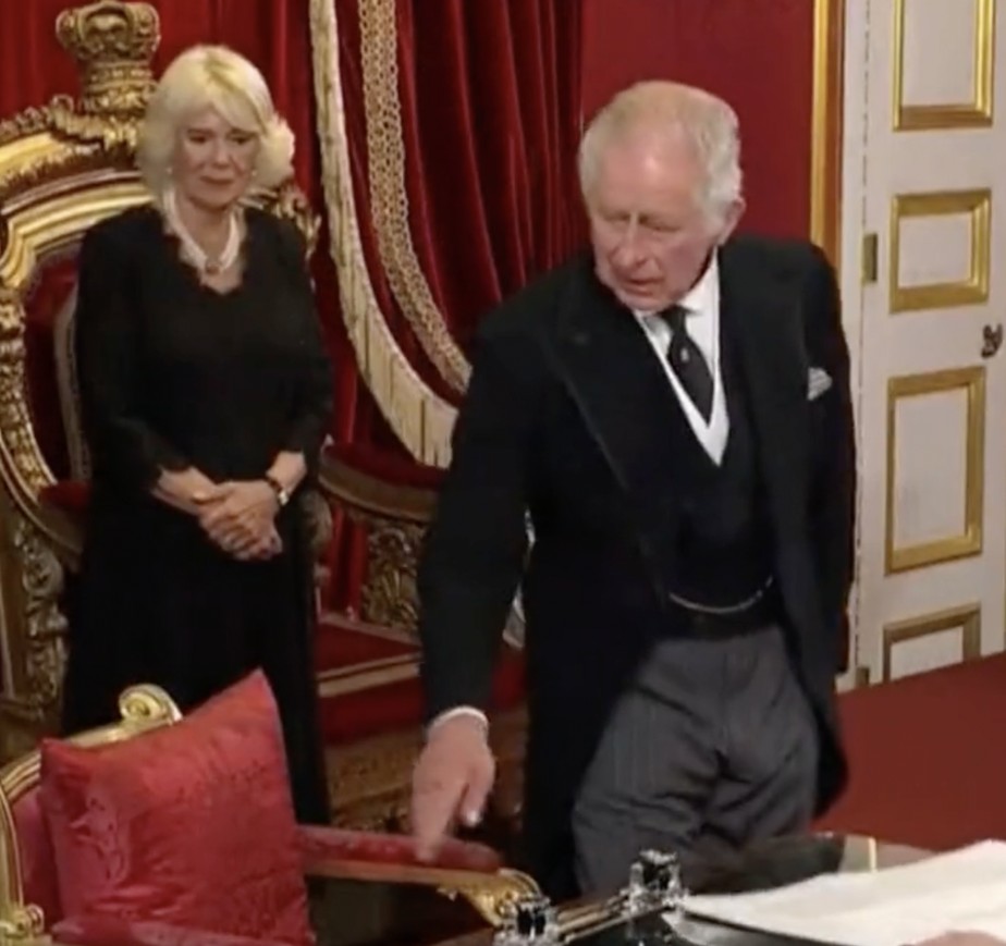 Rei Charles III faz aceno para que auxiliar retire caneta tinteiro de sua mesa