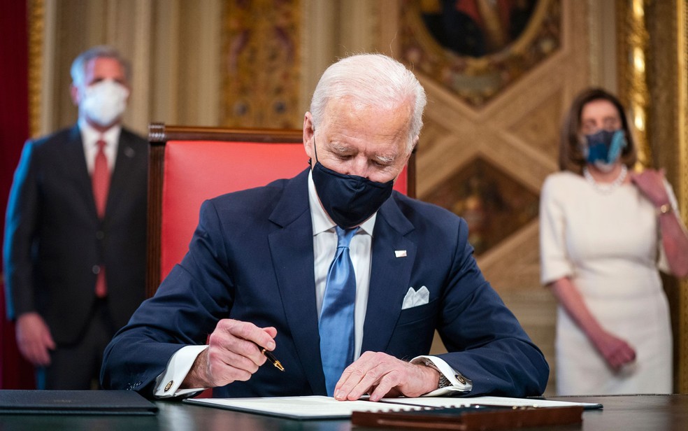 O presidente dos Estados Unidos, Joe Biden, assina seu termo de posse na sala presidencial no Capitólio, em 20 de janeiro de 2021 — Foto: Jim Lo Scalzo/Pool Photo via AP