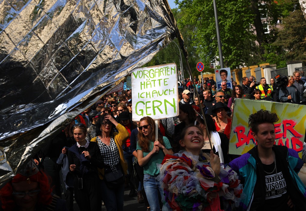 Manifestantes participam de um protesto satírico do Dia do Trabalho em Berlim, Alemanha, nesta quarta-feira (1º). "Também gostaria de ter um jardim em casa", diz a placa. — Foto: Christian Mang/Reuters