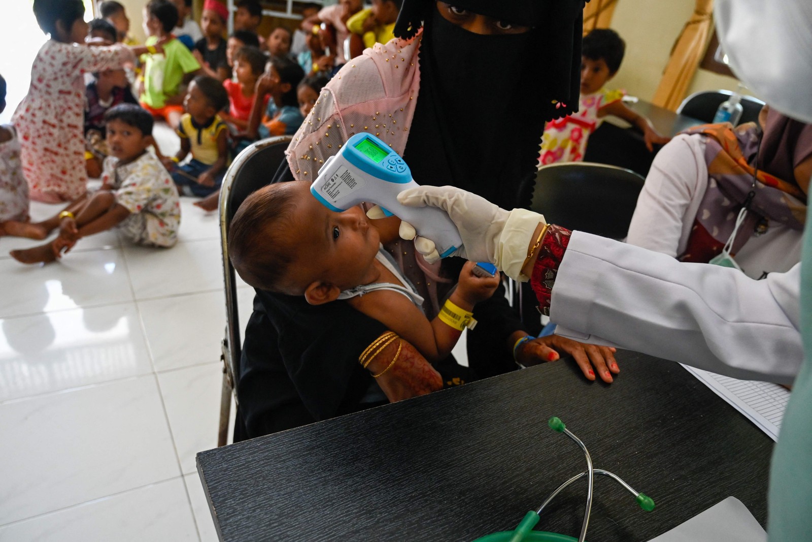 Um bebê tem sua temperatura verificada enquanto um grupo de crianças refugiadas rohingyas recebe vacinas contra poliomielite e rubéola organizadas pela Organização Internacional para as Migrações em um abrigo temporário em Ladong, província de Aceh — Foto: CHAIDEER MAHYUDDIN / AFP