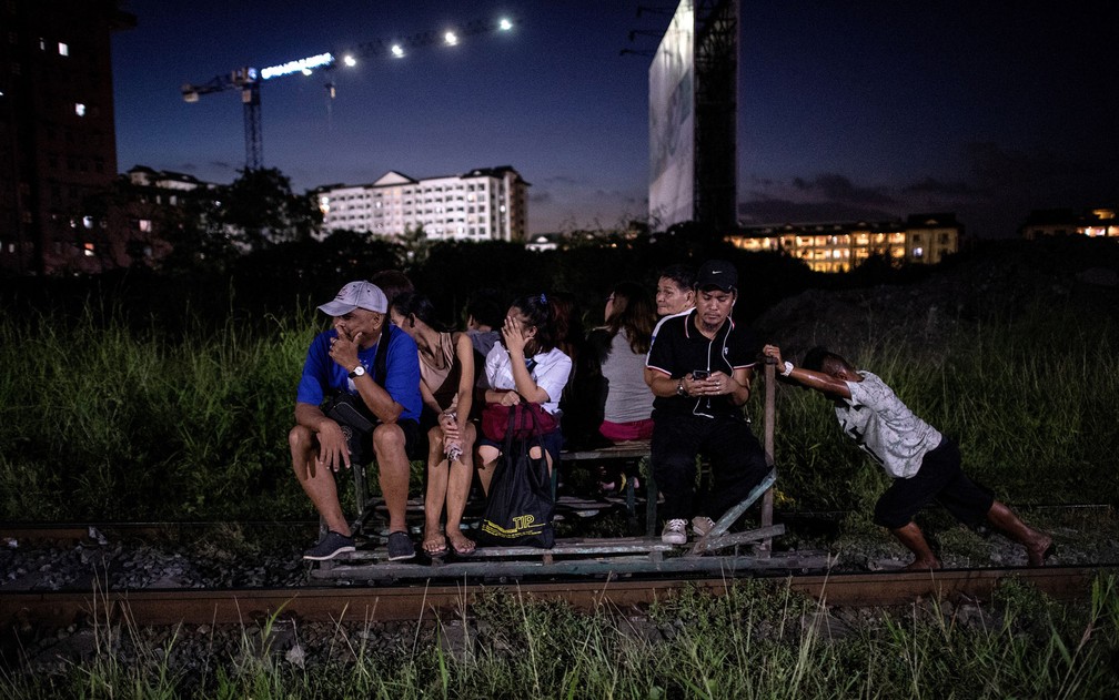 Foto de 19 de outubro mostra pessoas sendo transportadas em carrinho de passageiros em linha de trem de Manila — Foto: Noel Celis/AFP