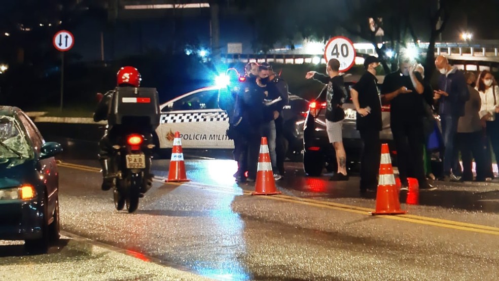 Pessoas na pista lateral da Epia Sul, no Park Way, onde jovem de 22 anos morreu após ser atropelada por dois carros  — Foto: TV Globo/ Reprodução