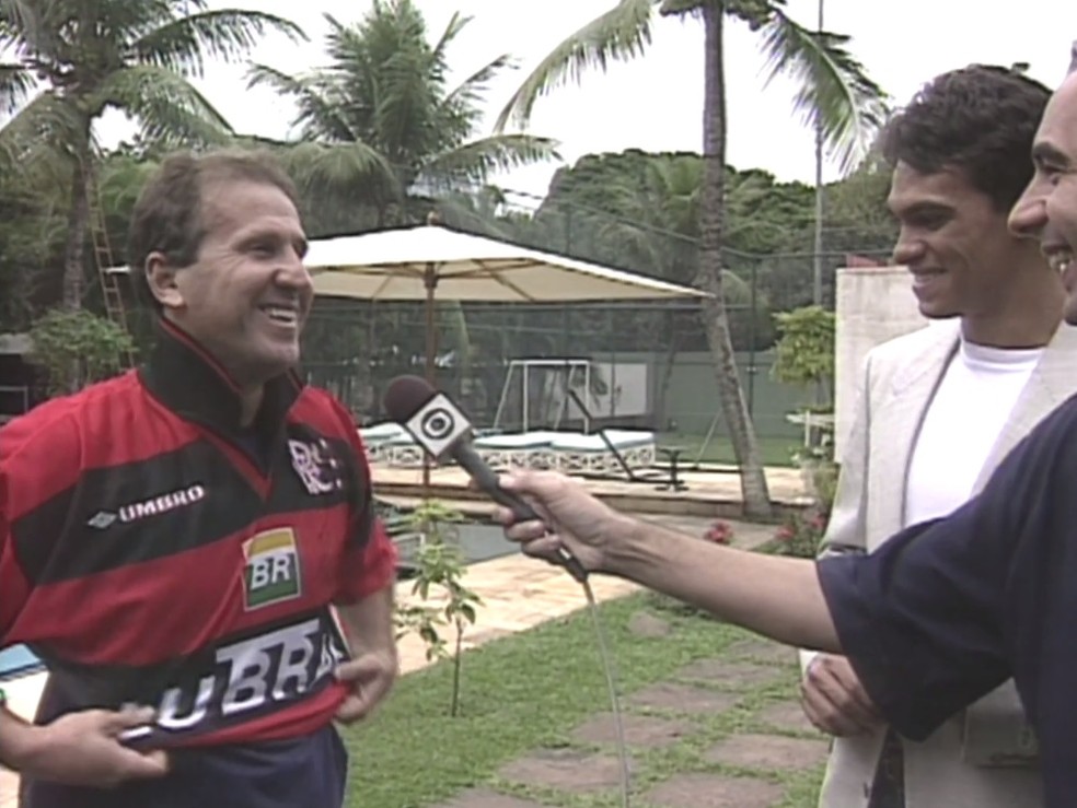 De blazer bege ao lado de R&eacute;gis R&ouml;sing, ex-atacante presenteia Zico com a camisa &mdash; Foto: Reprodu&ccedil;&atilde;o
