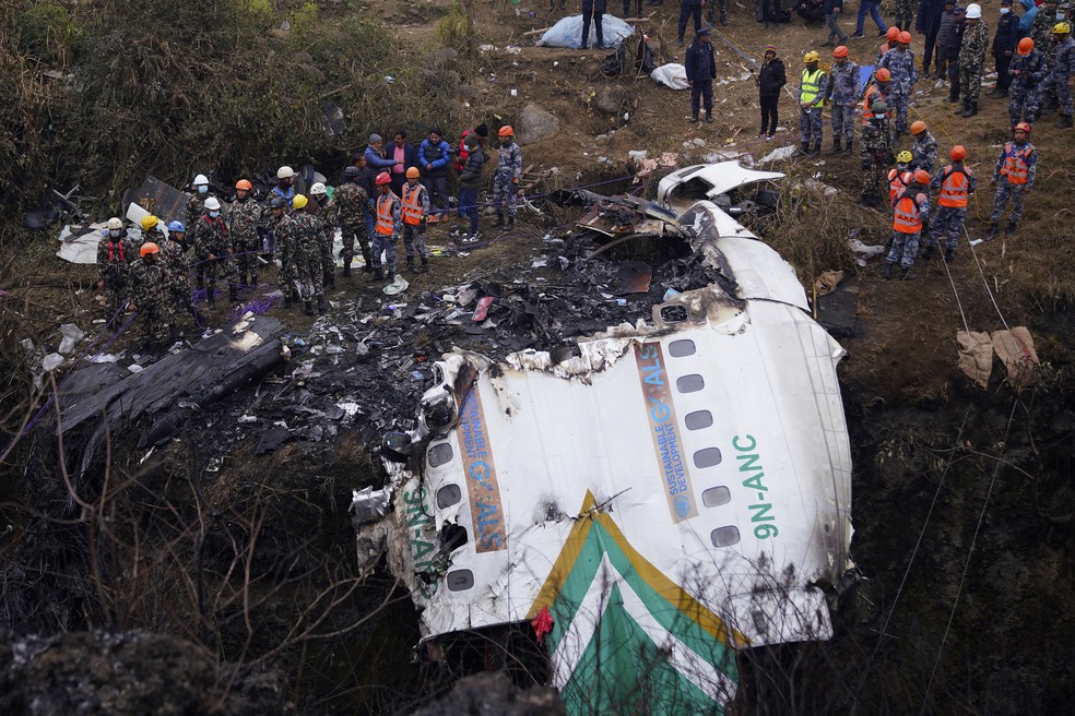 Equipes de resgate encaram destroços do avião que caiu no Nepal neste domingo (15) — Foto: Yunish Gurung/AP