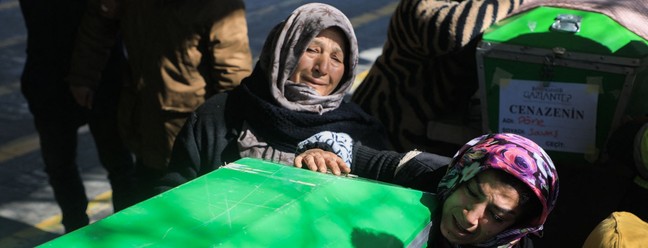 Parentes de vítima de terremoto abraçam caixão, em Gaziantep, na Turquia — Foto: Zein Al RIFAI / AFP