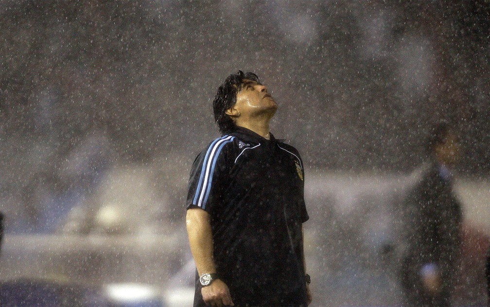 Diego Maradona, então técnico da seleção da Argentina, olha para o céu enquanto a chuva cai durante partida contra o Peru nas eliminatórias da Copa do Mundo em outubro de 2009, em Buenos Aires — Foto: Natacha Pisarenko/AP/Arquivo