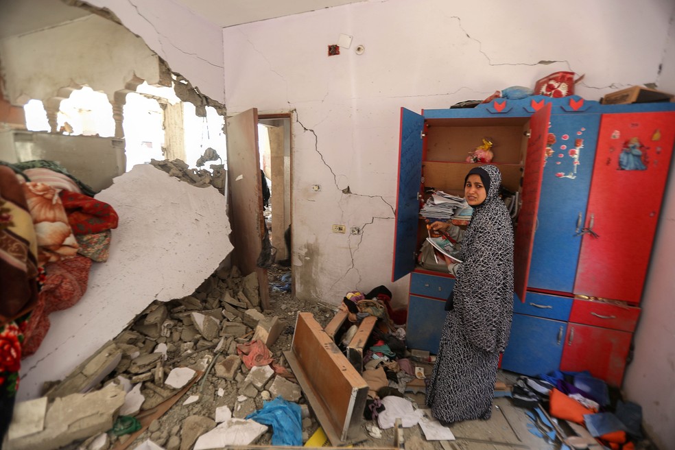 Uma mulher palestina reage enquanto recolhe seus pertences dentro de sua casa destruída após os ataques aéreos e de artilharia israelenses no norte da Faixa de Gaza, na sexta (14)    — Foto: Mohammed Salem/Reuters