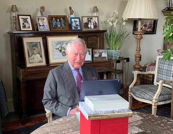 O Príncipe Charles em participação por videoconferência em inauguração de hospital escocês, com foto dele na companhia dos filhos Harry e William ao fundo (Foto: Instagram)