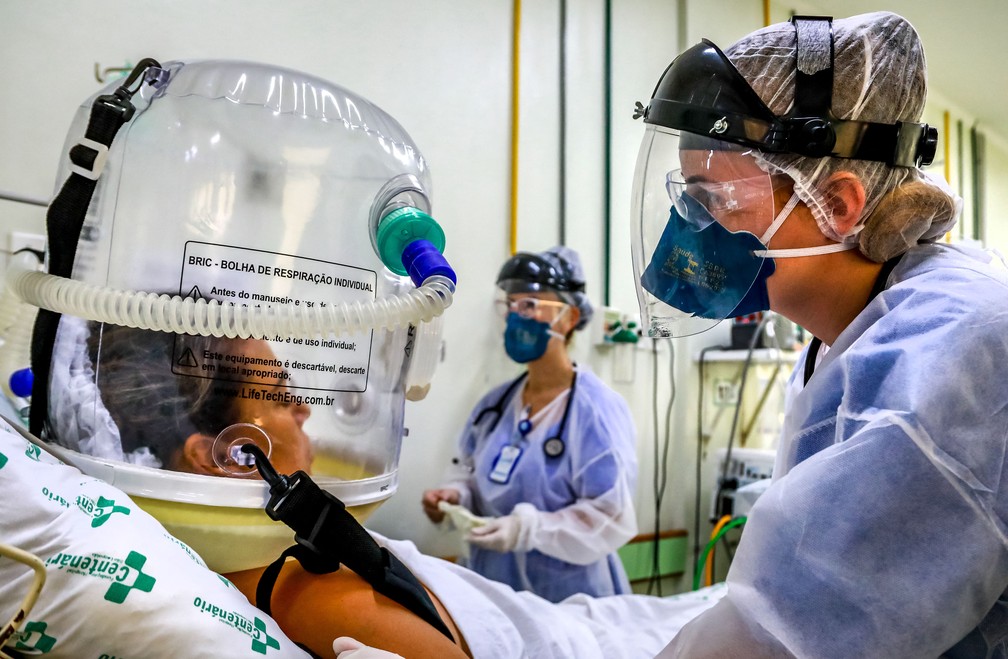 16 de abril - Profissionais de saúde cuidam de paciente internada com Covid-19 usando um balão com tecnologia não invasiva para reduzir a necessidade de intubação em uma UTI de São Leopoldo (RS) — Foto: Silvio Avila/AFP