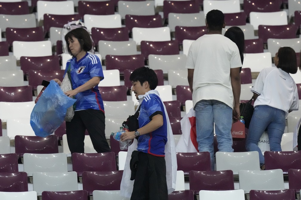 Torcedores japoneses limpam o Estádio Khalifa, em Doha, após a vitória do Japão sobre a Alemanha — Foto: Eugene Hoshiko/AP