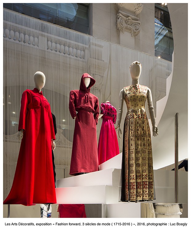 A installation of contemporary clothing featuring a hooded red jersey sweatshirt and skirt by Vetements, centre (Foto: Les Arts Décoratifs)