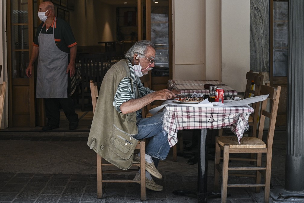 Homem almoça em restaurante reaberto de Atenas, na Grécia, nesta segunda (25) — Foto: Aris Messinis/ AFP