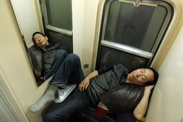 Dupla dorme desajeitada durante viagem de trem entre Guangzhou e Changchun (Foto: AFP)