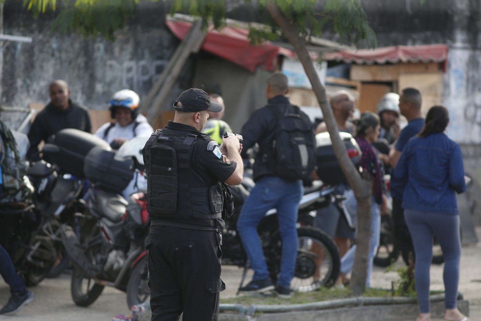 Policial em meio aos moradores durante a operação nos complexos da Penha e do Alemão. — Foto: Fabiano Rocha / Agência O Globo