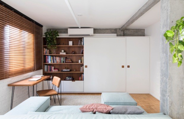 No living de 27 m² do apê na Bela Vista, em São Paulo, o escritório Iná Arquitetura projetou as salas de estar e de TV com um sofá duplo, da Cremme, voltado para os dois ambientes (Foto: Maíra Acayaba / Divulgação)