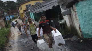 Pessoas retiram pertences de suas casas afetadas por fortes chuvas e um deslizamento de terra na comunidade Vila dos Milagres, bairro do Barro, em Recife — Foto:  SERGIO MARANHÃO / AFP