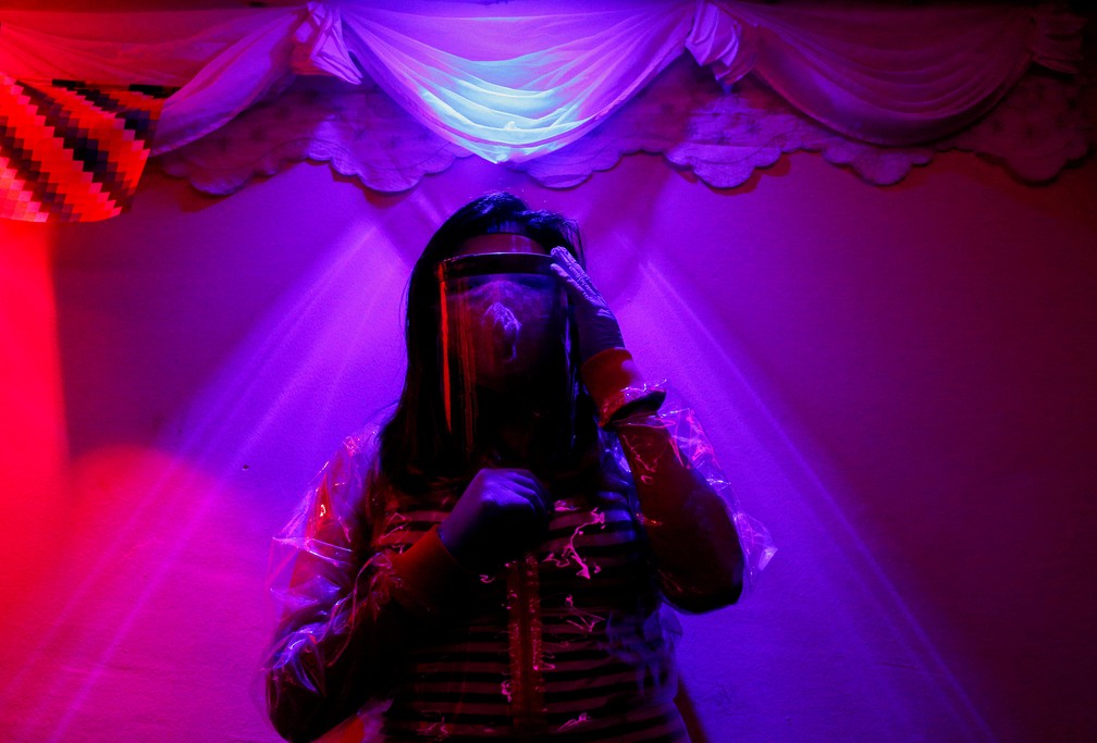 15 de julho - Profissional do sexo com máscara protetora, protetor facial e luvas posa para foto no clube onde trabalha, em meio à pandemia de coronavírus (Covid-19), nos arredores de El Alto, em La Paz, na Bolívia — Foto: David Mercado/Reuters