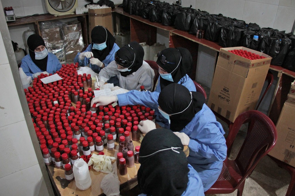 Mulheres trabalham na produção de remédios artesanais no hospital de Dula, na Síria (Foto: Hamza Al-Ajweh/AFP)