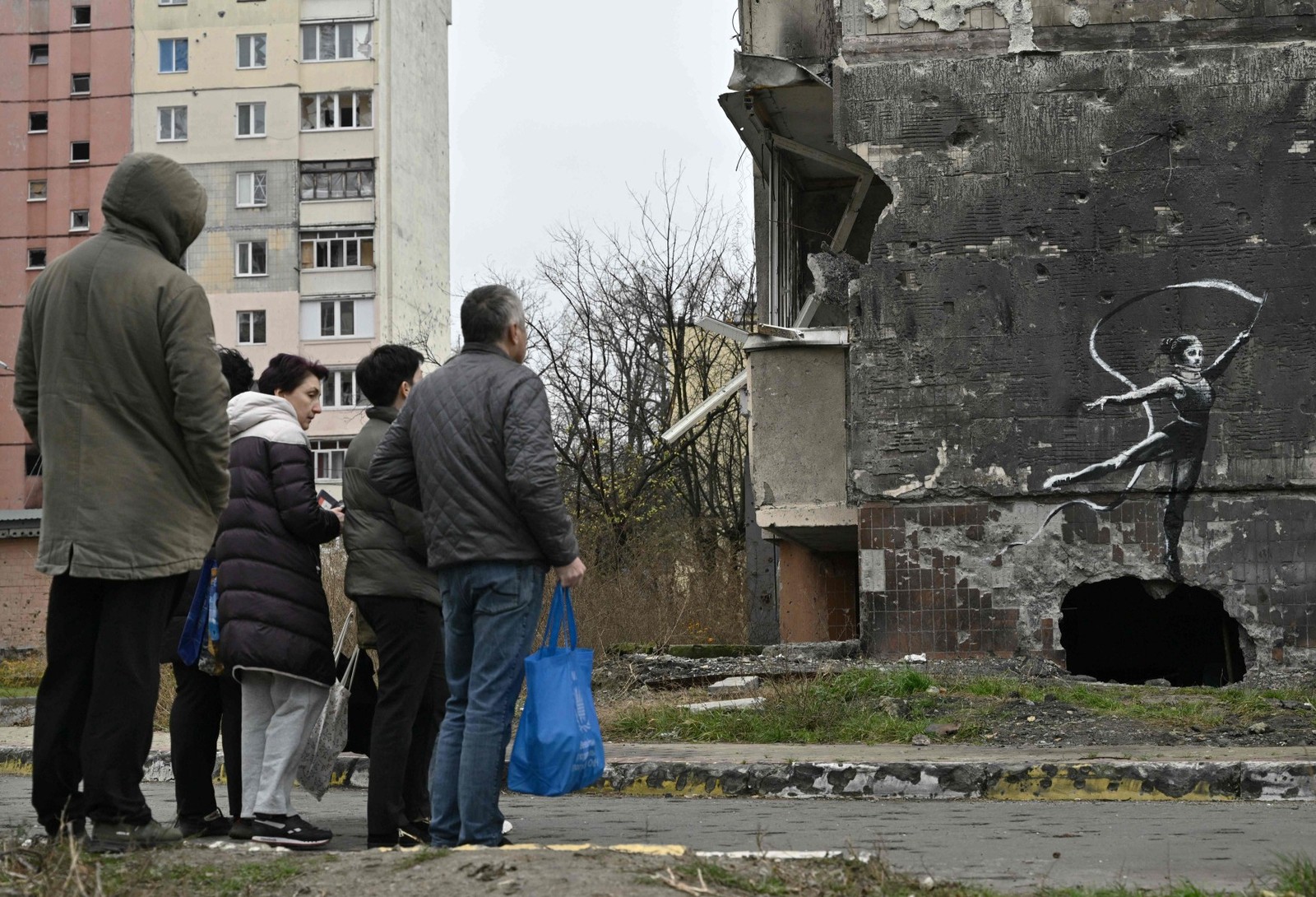 Moradores observam obra 'estilo Banksy' na cidade de Irpin em 12/11/22 — Foto: Genya SAVILOV / AFP