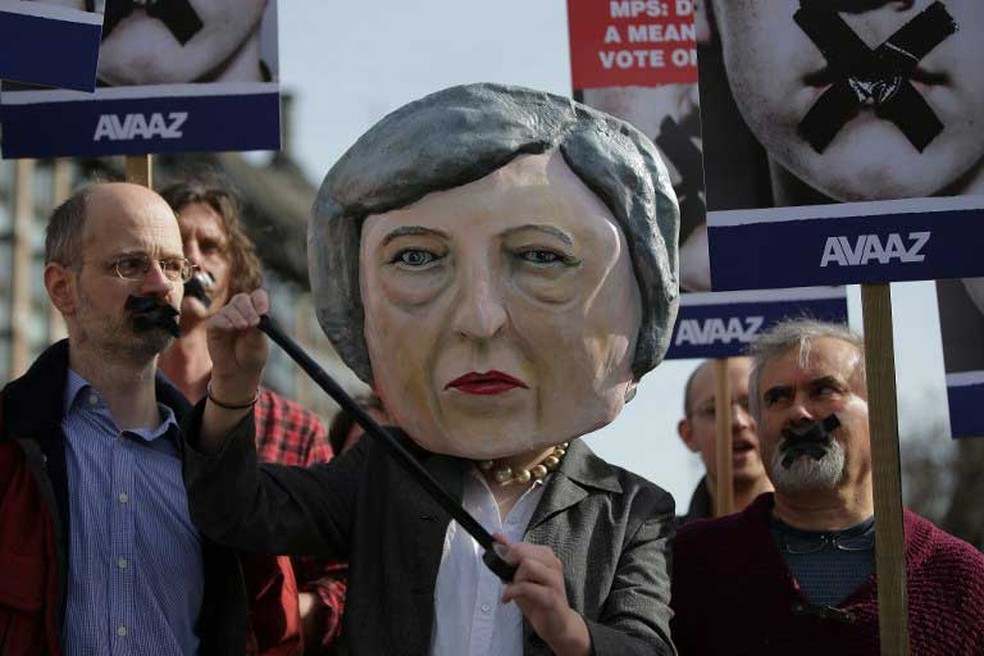 Manifestante coloca máscara da premiê britânica, Theresa May, durante protesto em frente ao Parlamento, em Londres, nesta segunda-feira (13) (Foto: Daniel Leal-Olivas / AFP)