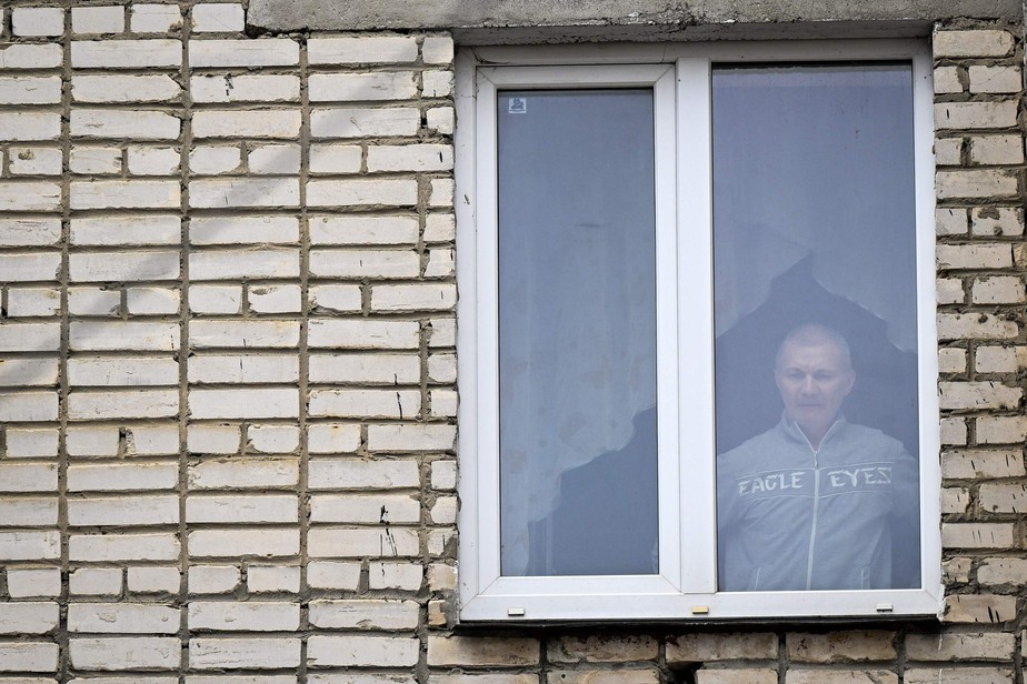 Alexei Moskalyov — pai de Maria Moskalyova, uma menina de 13 anos que fez um desenho crítico à guerra na Ucrânia na escola — olha pela janela de seu apartamento em 23 de março de 2023