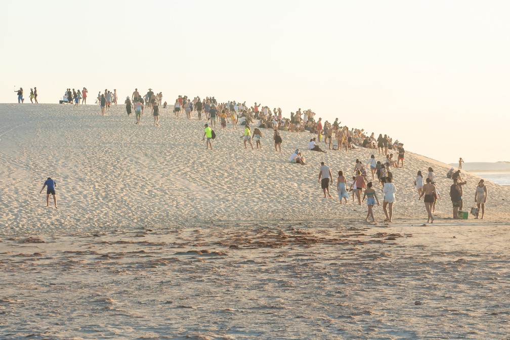 Com a aproximação do pôr do sol, turistas caminham até a duna da praia central — Foto: Celso Tavares/G1