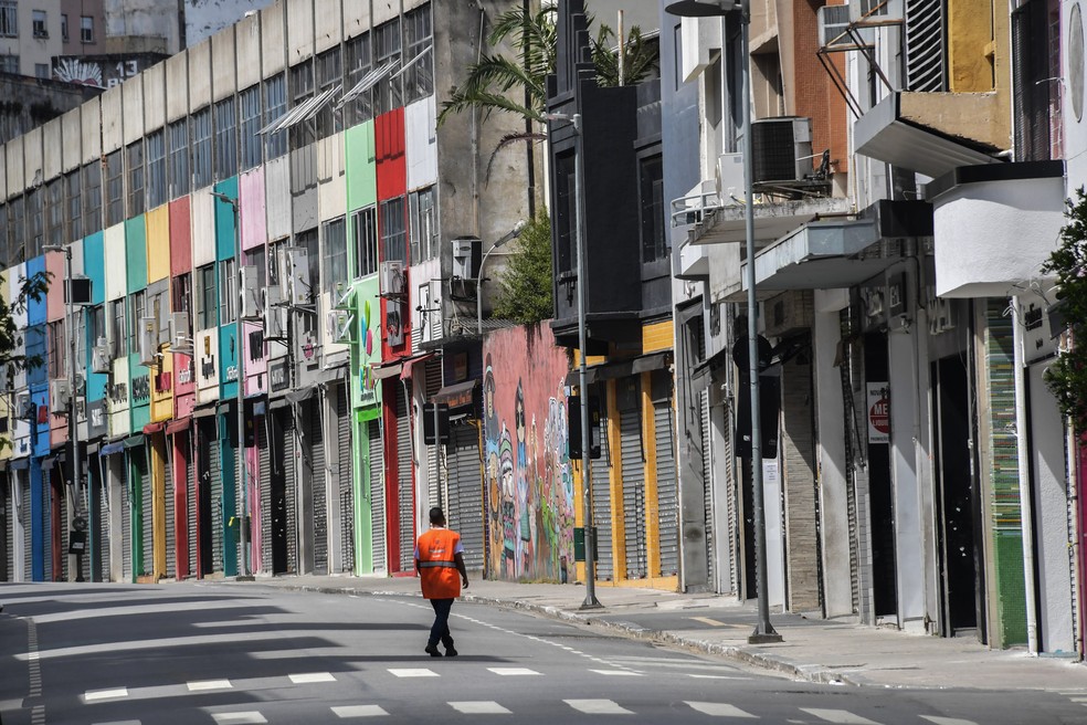 SÃO PAULO - Um homem caminha por uma rua comercial vazia no centro de São Paulo nesta terça-feira (24) depois que o governo da cidade decretou o fechamento de lojas como medida de precaução contra a disseminação do novo coronavírus  — Foto: Nelson Almeida/AFP