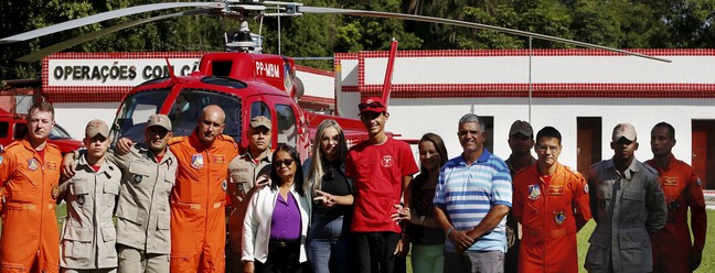 Christian e sua família posam junto aos socorristas do Corpo de Bombeiros — Foto: Fabiano Rocha / Agência O Globo