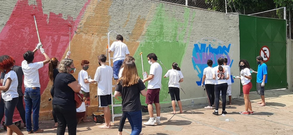 Alunos da Escola Estadual José Romão, de Piracicaba, na execução da pintura do muro — Foto: Júlia Heloisa Silva/G1 Piracicaba