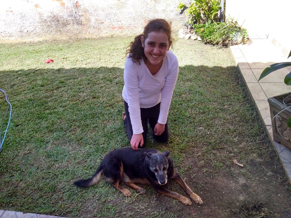 Franciny Tortato Silva, de 19 anos, que espera pelo transplante de pulmão, brinca com o cachorro 'Black' no quintal de casa. (Foto: Arquivo pessoal)