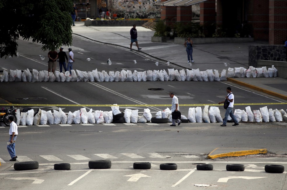 Pedestres caminham em meio a barricadas em Caracas, na Venezuela (Foto: AP Photo/Ariana Cubillos)