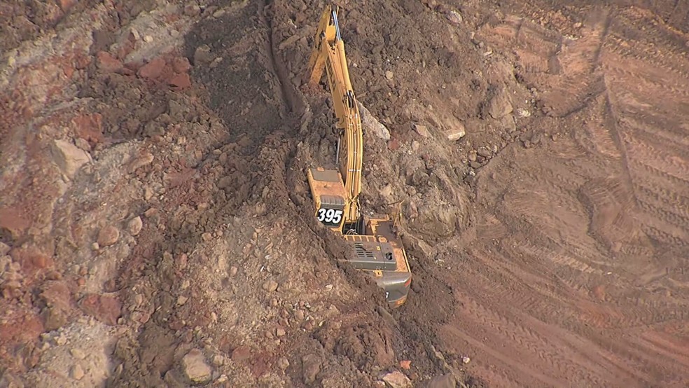 Retroescavadeira foi soterrada após deslizamento de terra de talude em Sarzedo — Foto: TV Globo