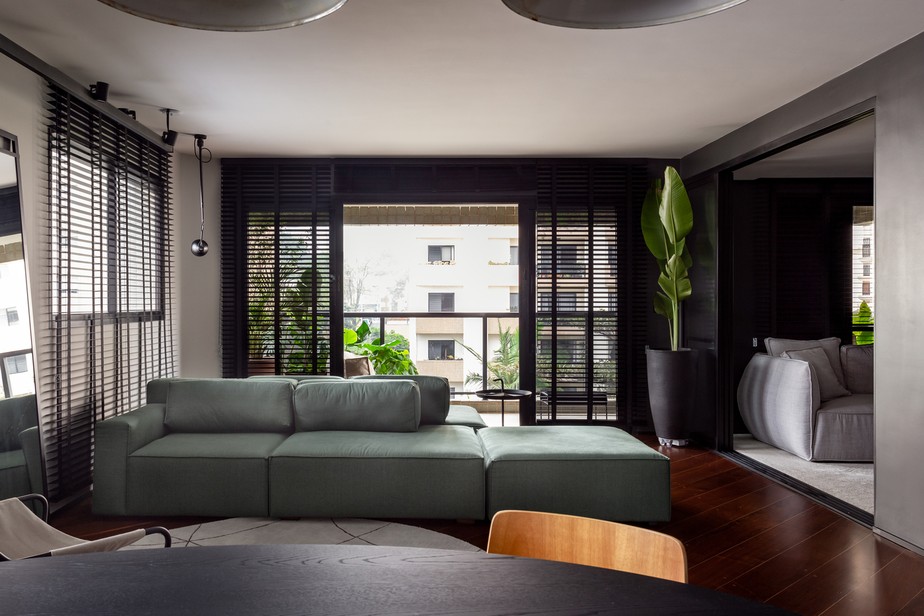 SALA | O sofá verde da Cremme está voltado para a área do estar, mas permite se conectar com a varanda. O preto torna o ambiente mais moderno. Tapete redondo é da Ondo