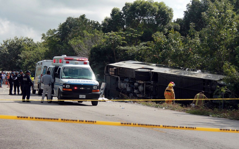 Ambulância é vista ao lado de ônibus de turistas que sofreu acidente em Mahahual, Quintana Roo, no México, na terça-feira (19) (Foto: Novedades de Quintana Roo via AP)