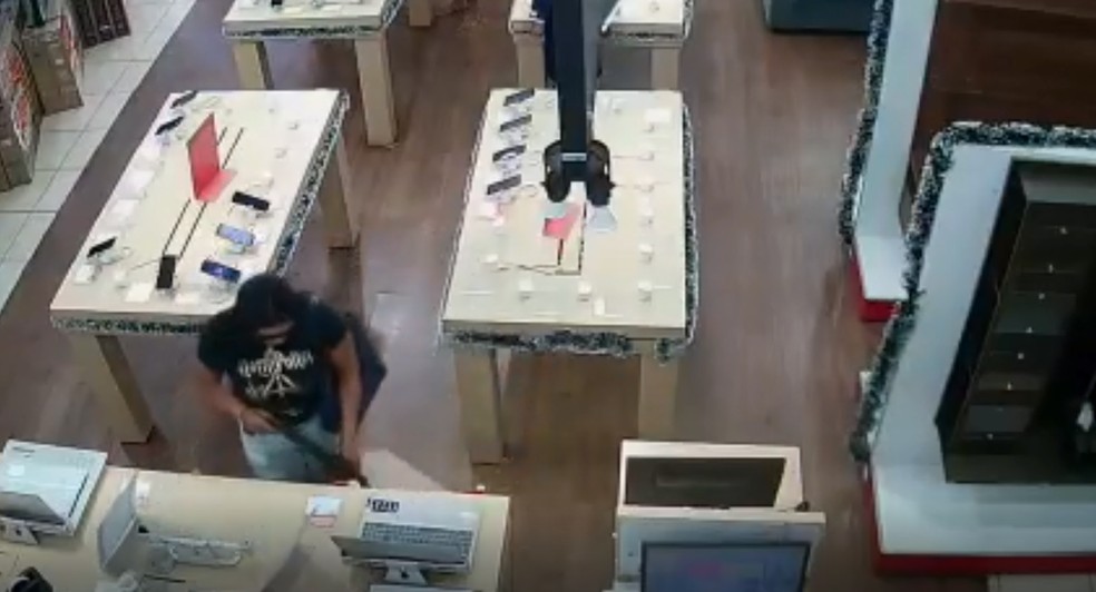 Comparsa coloca notebook em sacola e, na sequência, caminha em direção à saída da loja.  — Foto: Reprodução
